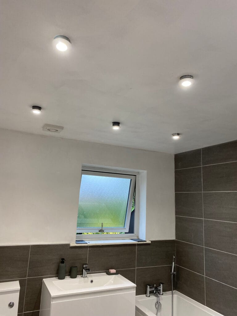 Modern bathroom with downlights and frosted window.