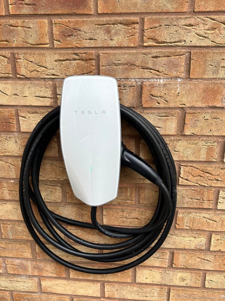 Tesla wall charger mounted on brick wall.