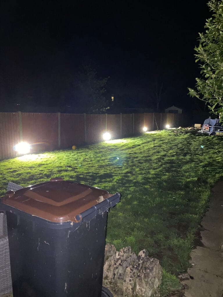 Night garden with bright lights and bin.